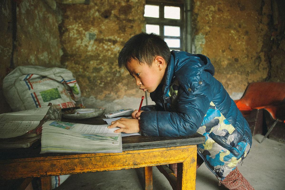 乡村小学留守儿童趴在课桌上望向校门