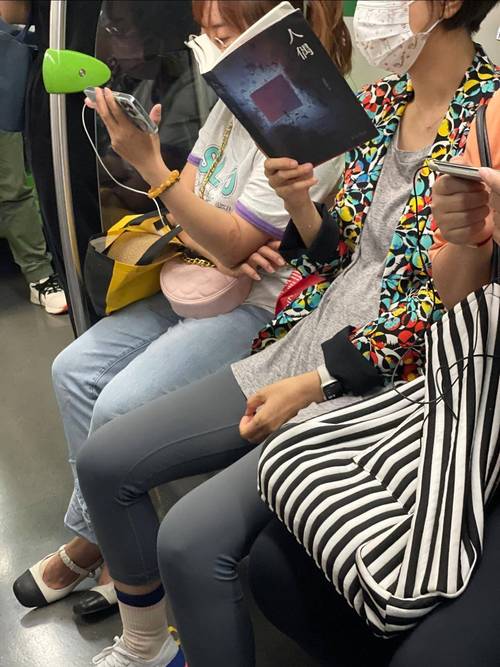 地铁上拿手机阅读电子书的女生侧影