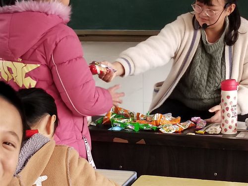 小学教室课桌下女生递零食给同班女生场景