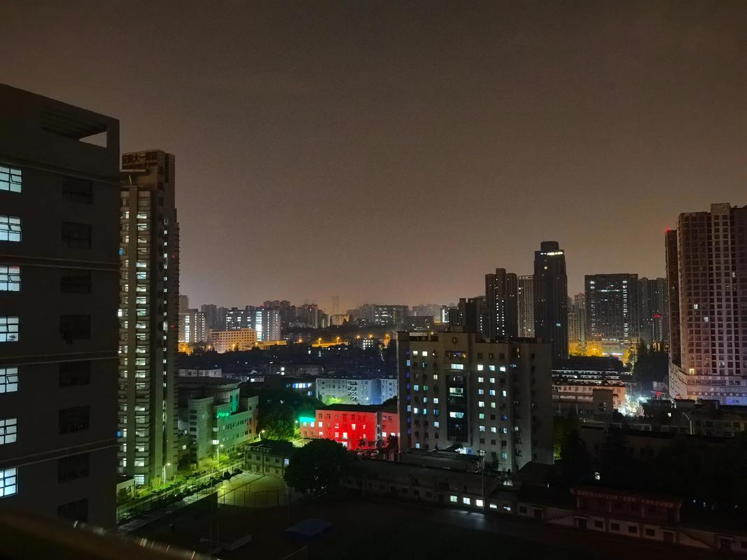 学生深夜独自站在阳台望向远方夜景缓解学习压力