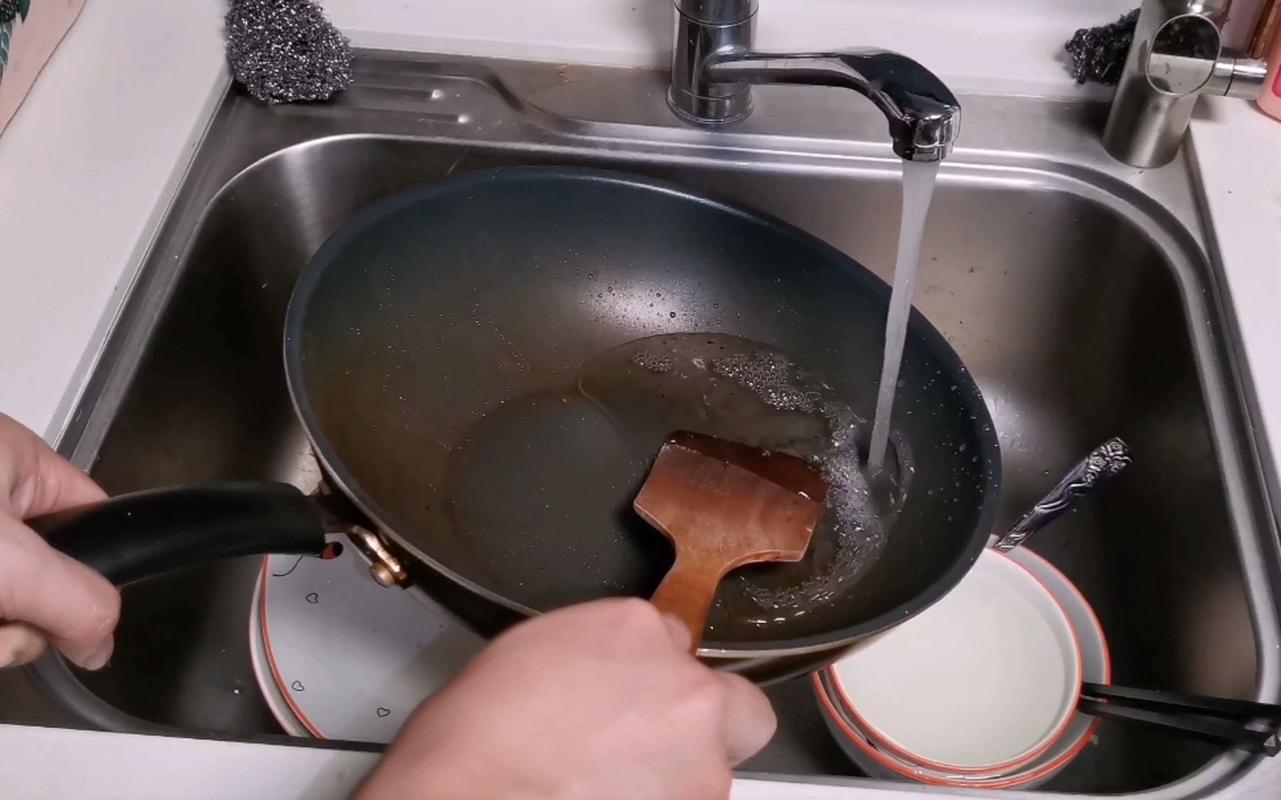刚炒完菜的热铁锅对着冷水冲的厨房场景