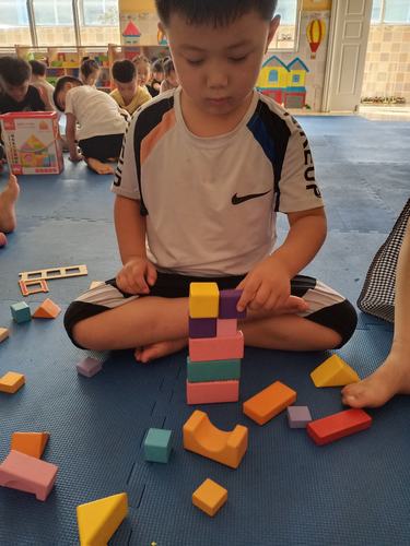 3岁宝宝坐在地垫上专注拼大颗粒积木的实拍图