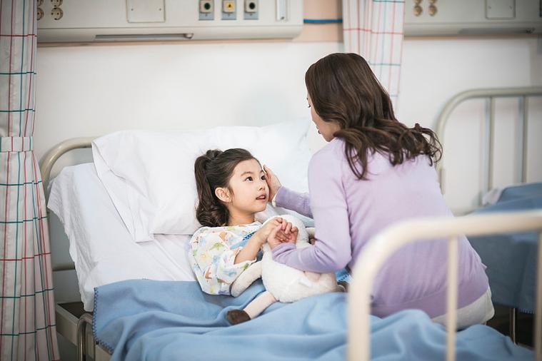 住院儿童坐在病床上和家长一起看窗外的暖光照片