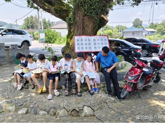 乡村孩子在树下听老师讲手写绘本