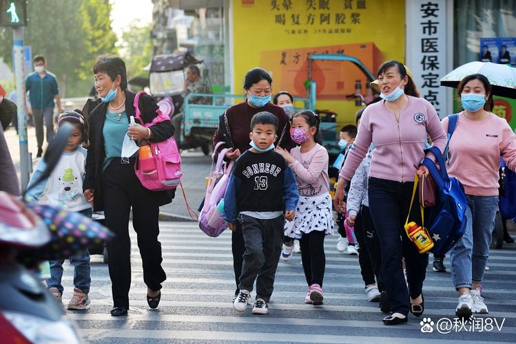 小学生背着书包在斑马线旁唱上学歌的实景图