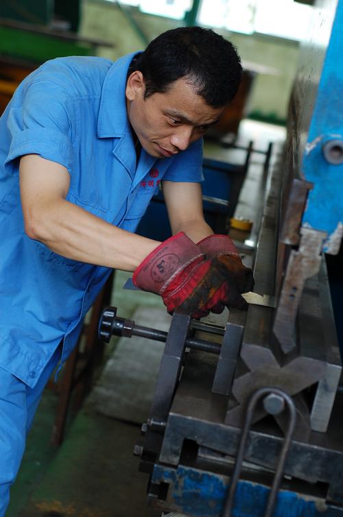 机械车间工人佩戴工业手套操作冲床