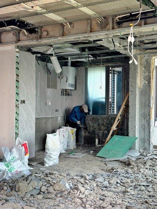 装修工人正在小心拆除旧瓷砖避免损坏地暖管