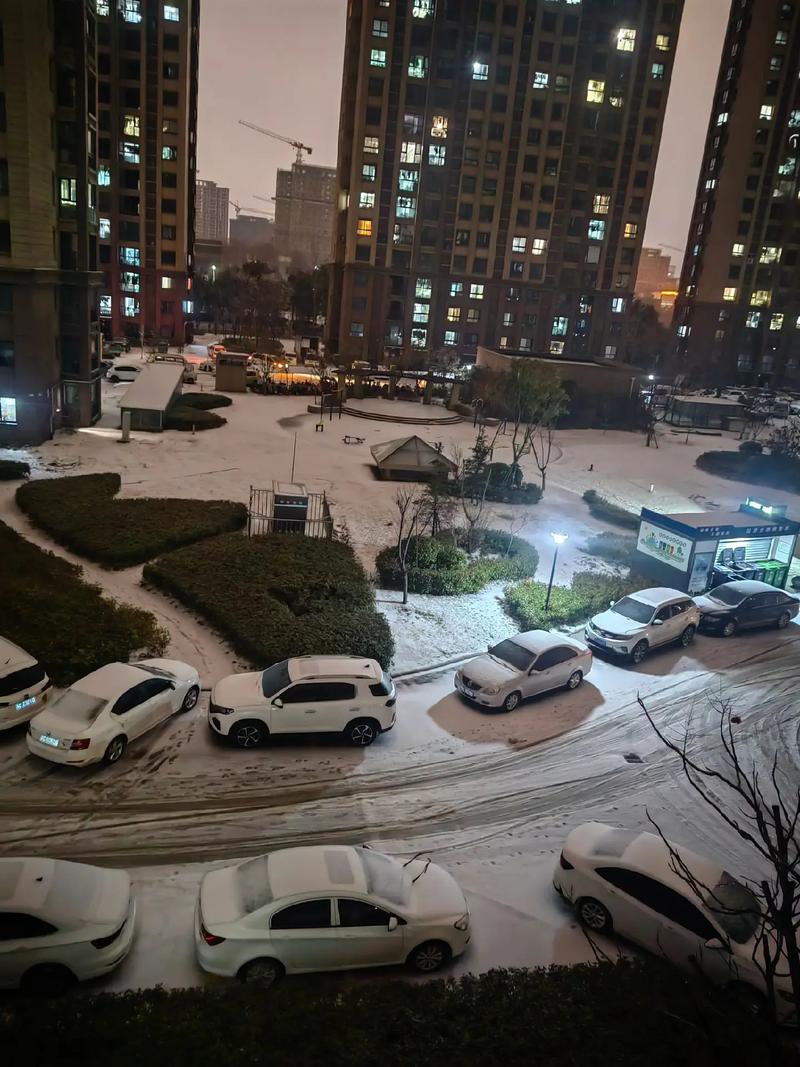 深夜阳台落地窗外落雪城市街景