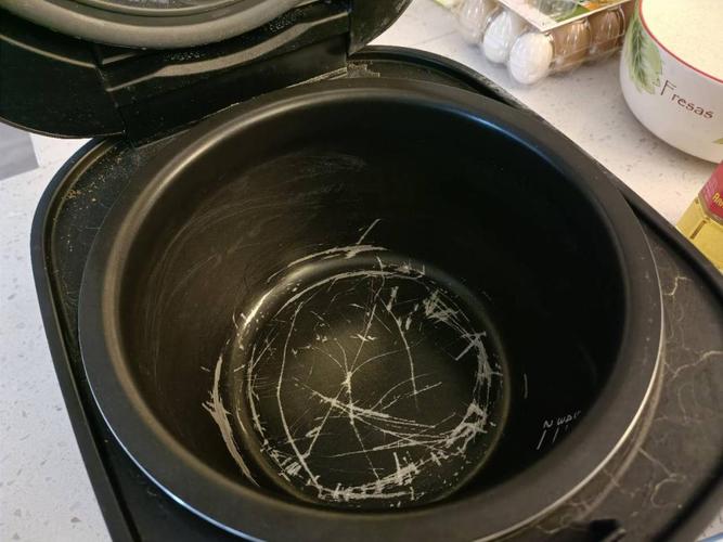 手举着带细微划痕的电饭煲内胆对着客厅灯光