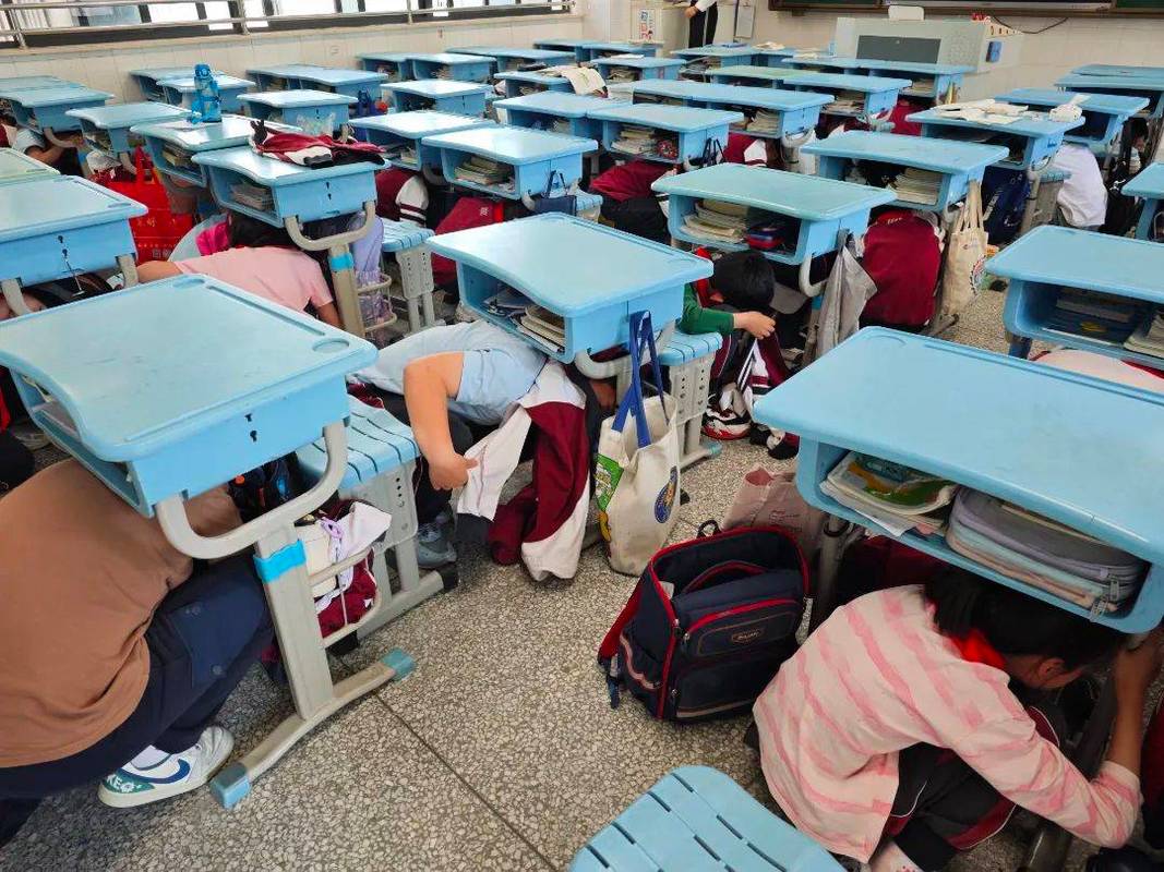 学校地震应急疏散演练学生躲在课桌下避险