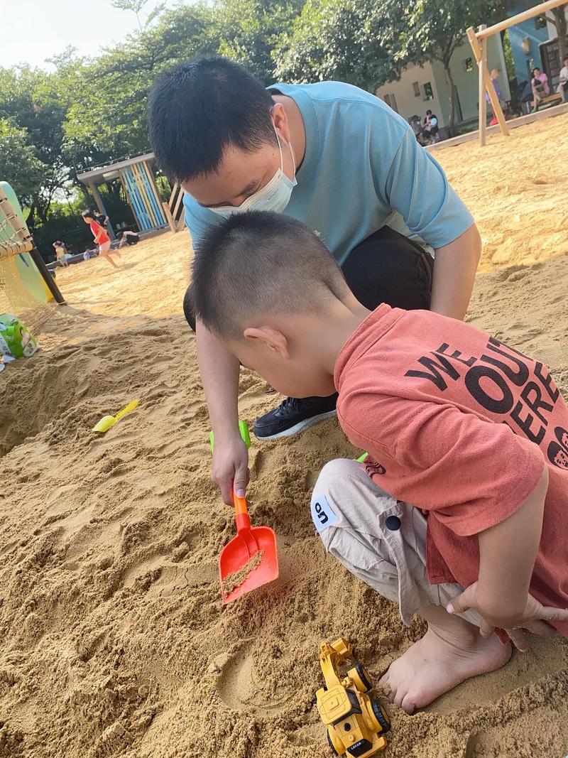 小区沙坑边爸爸给儿子占沙位陪玩