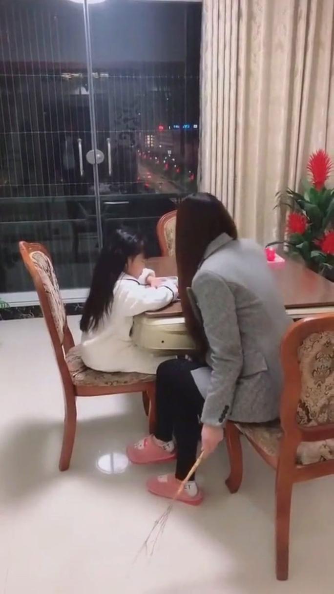 母亲和孩子一起看数学试卷并轻抚孩子后背